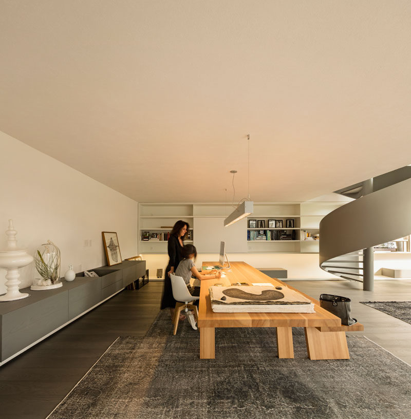 This modern house interior has an open work area with a large wood table and a floating sideboard. #ModernHomeOffice #LargeWoodTable #ModernInterior