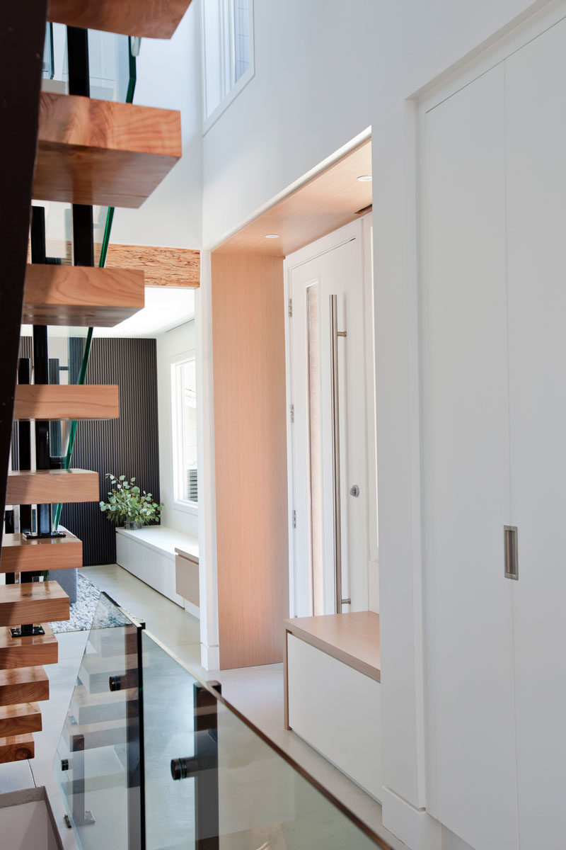 Inside this modern house, the entryway is lined in wood with a built-in bench beside the front door. #FrontDoor #Entryway