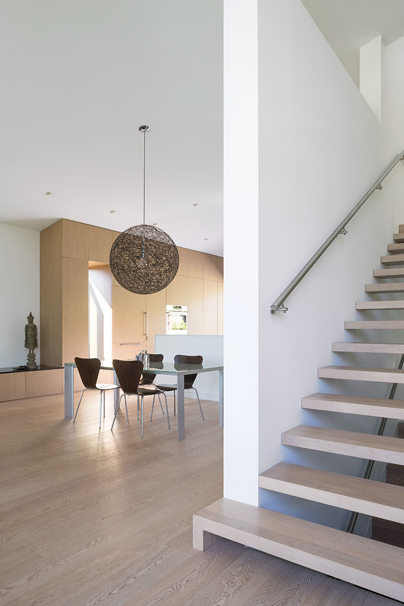 Wood stairs lead up from the main floor of this modern house, to the partial third storey that contains a new office, and a master bedroom and ensuite. #Stairs #ModernInteriorDesign #WoodStairs