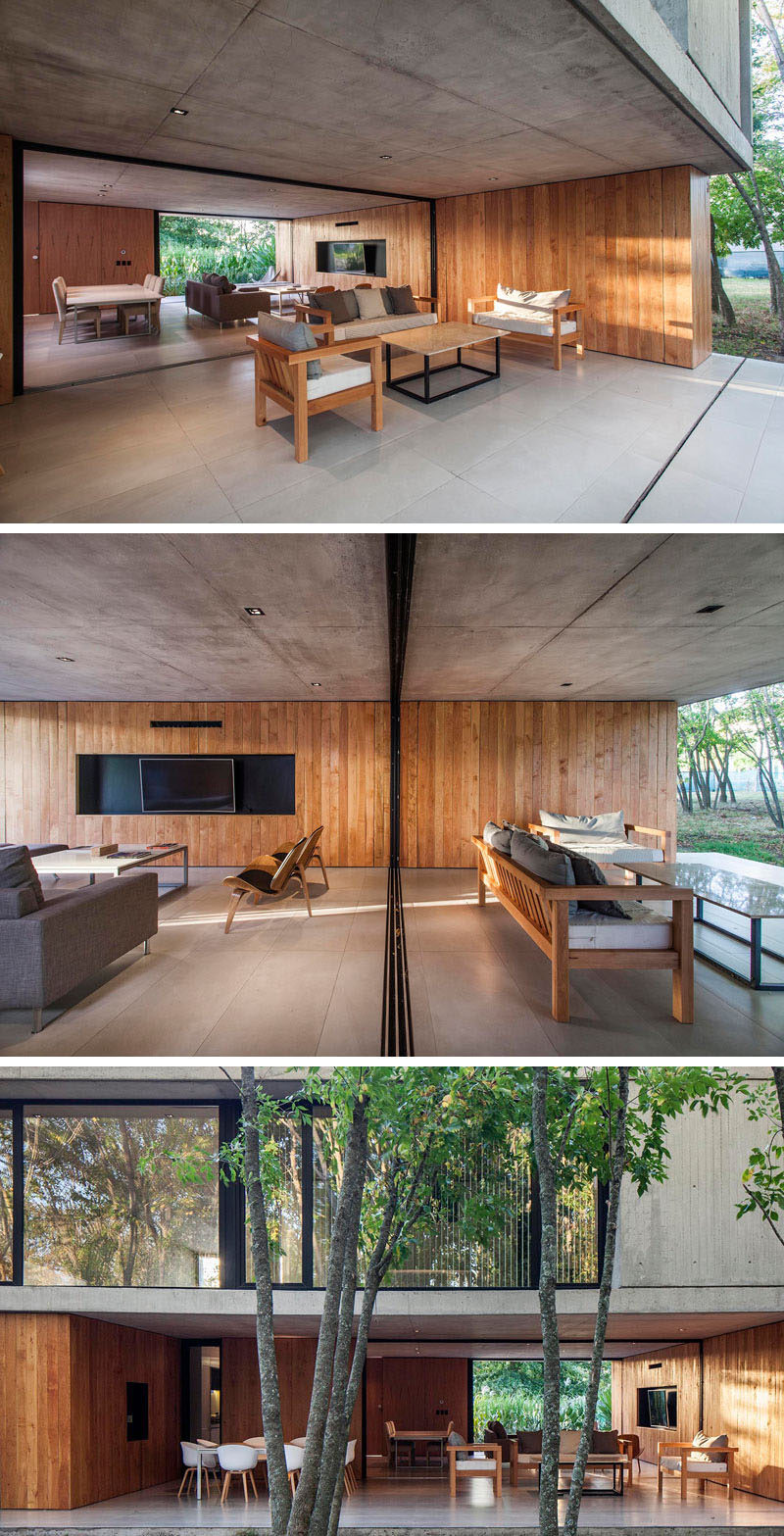 The interior concrete ceiling and wood wall of this modern house, extends to provide shade and protection for the outdoor living room and alfresco dining area. #Architecture #InteriorDesign #WoodWall #ModernHouse