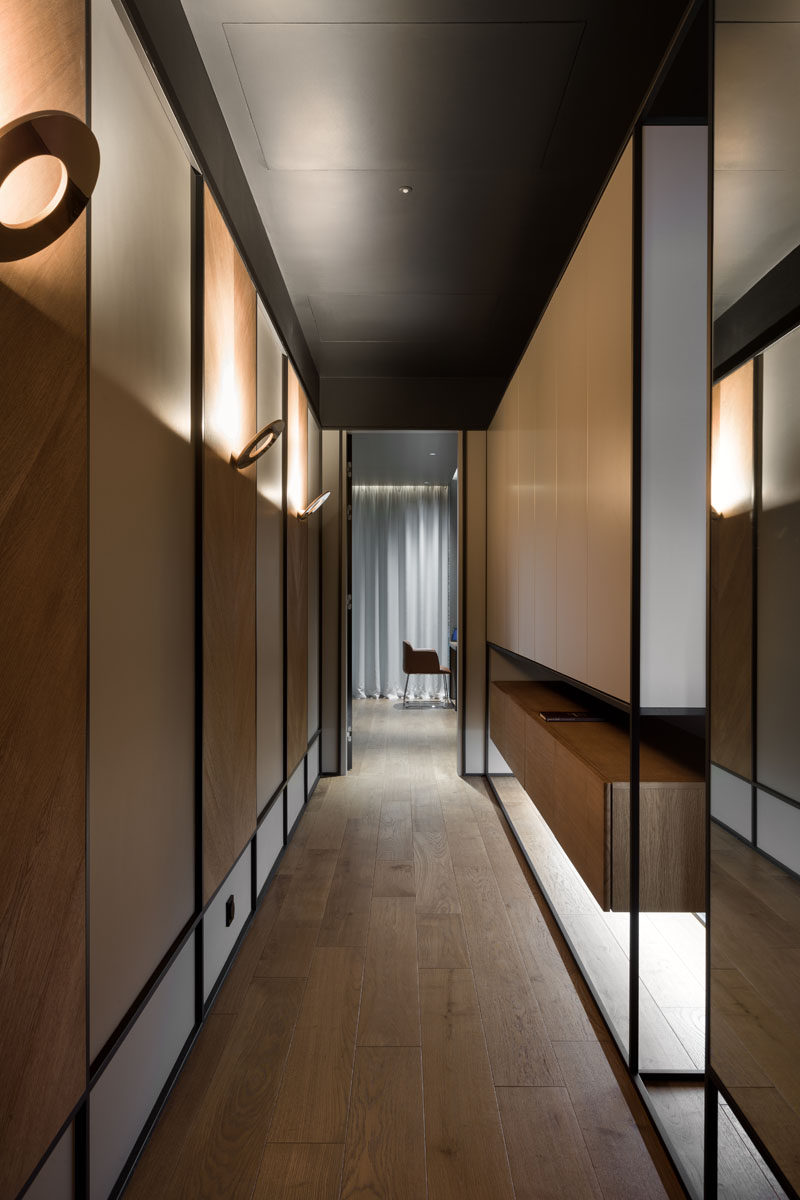 Hallways with wood panels highlighted by scones lead to the more private areas of this modern home, like the home office / guest room, and the bedrooms. #Hallway #ModernSconce