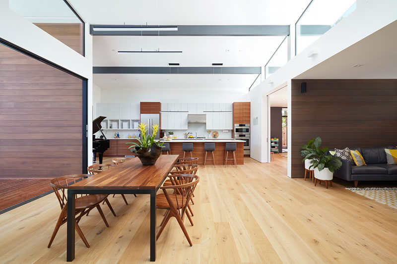 The dining table is central to the open interior of this modern house, and the clerestory windows that meet the high sloping ceiling help to make the space light and airy. #ModernDining #Windows #HighCeiling