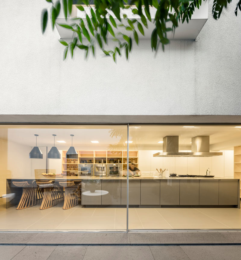 In this modern kitchen, a large island with space for seating is central to the room, while open wood shelving surrounds the wall ovens. #ModernKitchen #KitchenDesign #LargeKitchenIsland