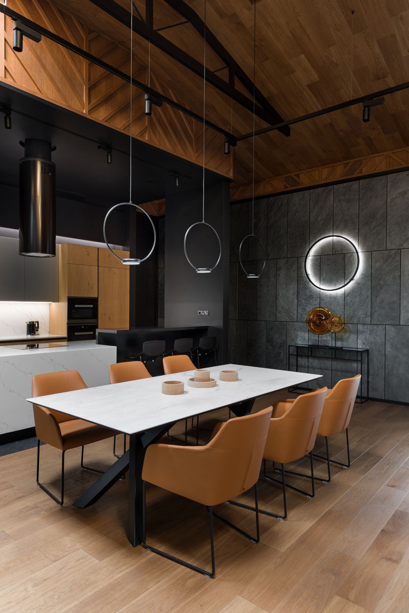 The dining area in this open plan interior, is positioned beneath three minimalist circular pendant lights, separates the living room from the kitchen. #DiningTable #DiningRoom