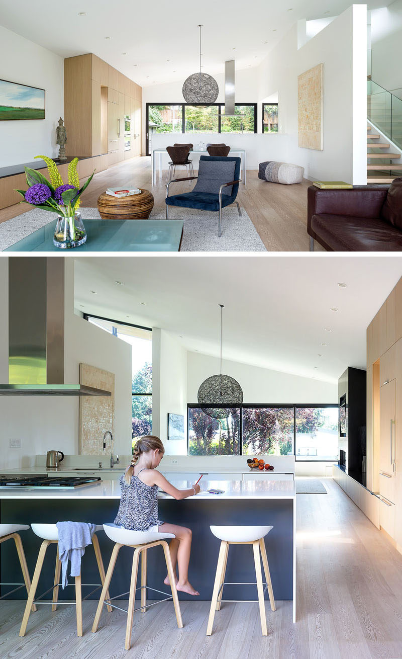 The main floor of this modern house is dedicated to the living room and dining room, and located behind a pony wall is the kitchen, that looks out towards the backyard, however it can also see through to the street at the front of the house. #OpenPlanInterior #PonyWall #InteriorDesign #ModernInterior