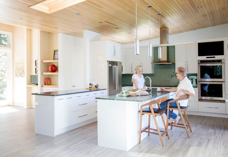 This modern kitchen features white cabinetry and a centrally located island with room for seating. #ModernKitchen #KitchenDesign #WhiteKitchen