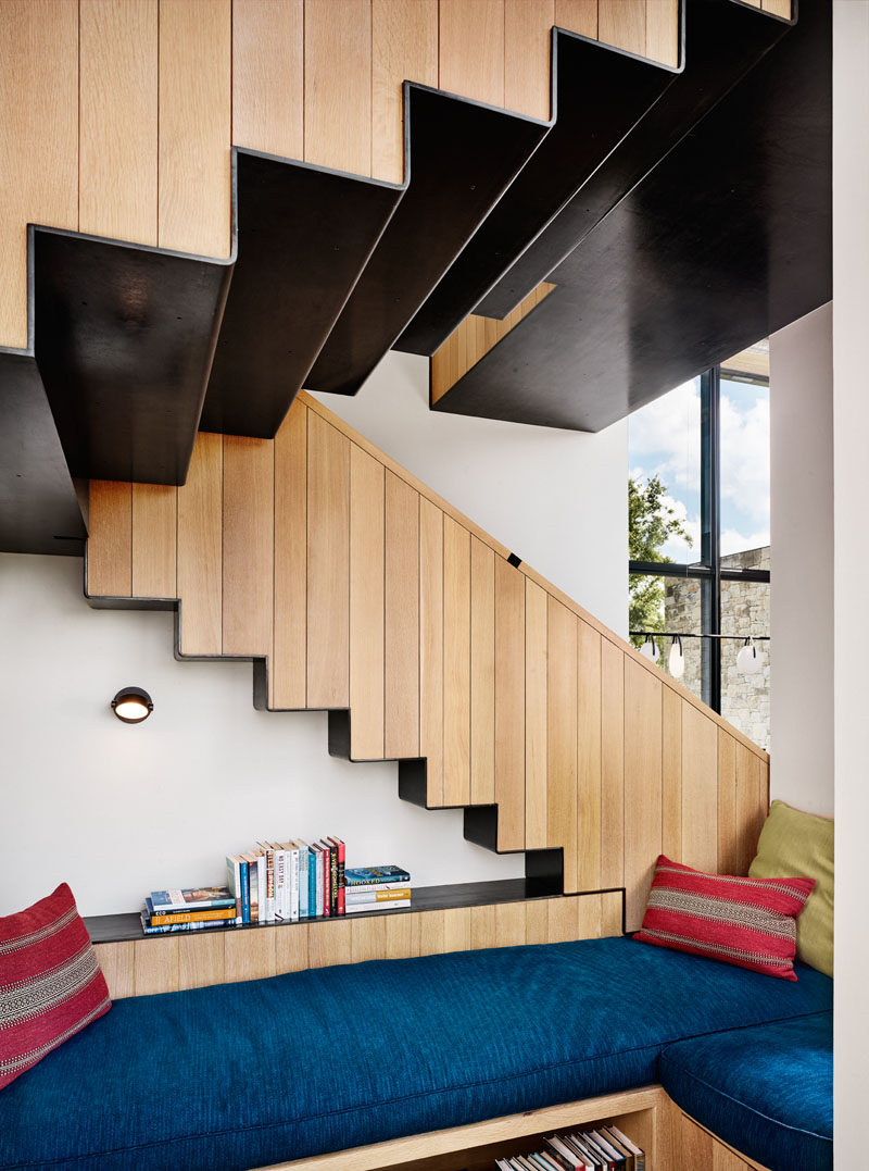 This modern house features steel and wood stairs, and located underneath, a small reading area with blue cushioned benches. #Stairs #StairDesign