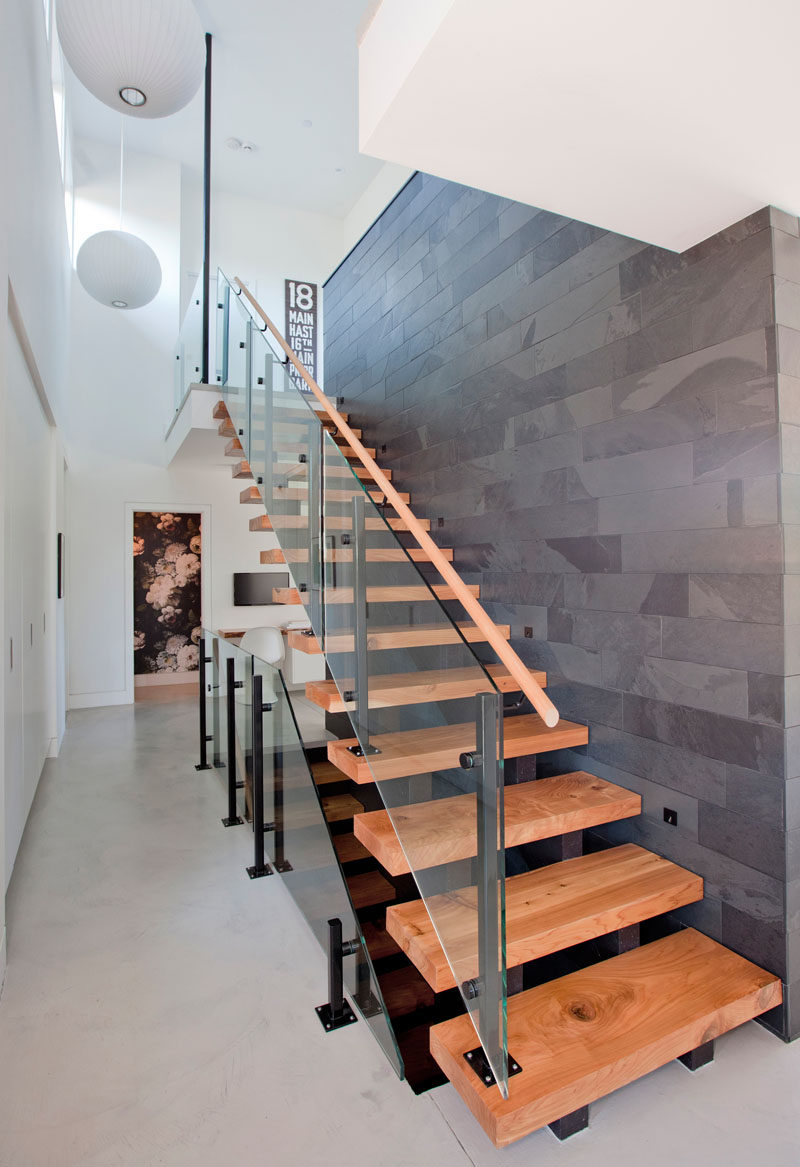 This modern house features steel and wood stairs by the front door that lead to the upper and lower levels of the home. #Stairs #ModernStairs #WoodStairs