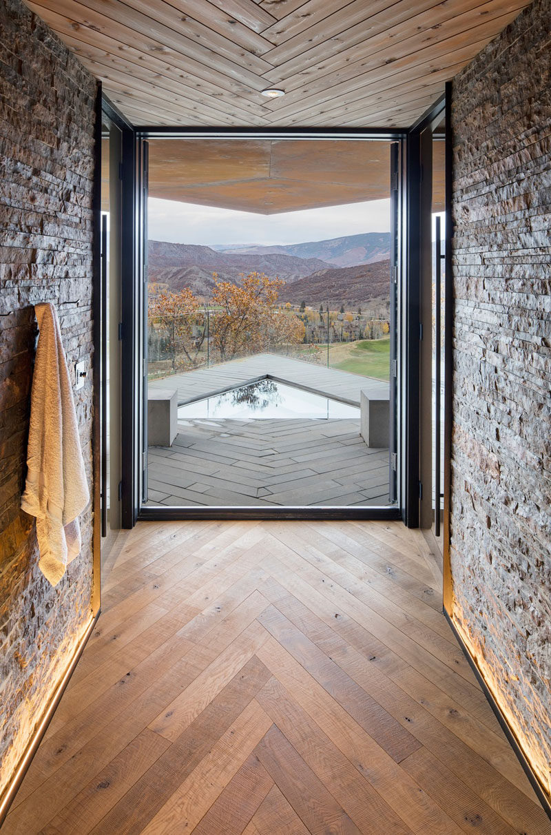 In this modern mountain house, wood installed in a herringbone pattern features on the ceiling and on the floor, while a large floor-to-ceiling picture window frames the view of the mountains. #Windows #Flooring #Ceiling