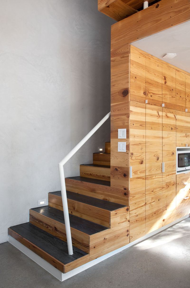 Wood stairs with charred wood treads and a white handrail lead to the second floor of this modern apartment. #WoodCabinetry #Stairs #StairDesign