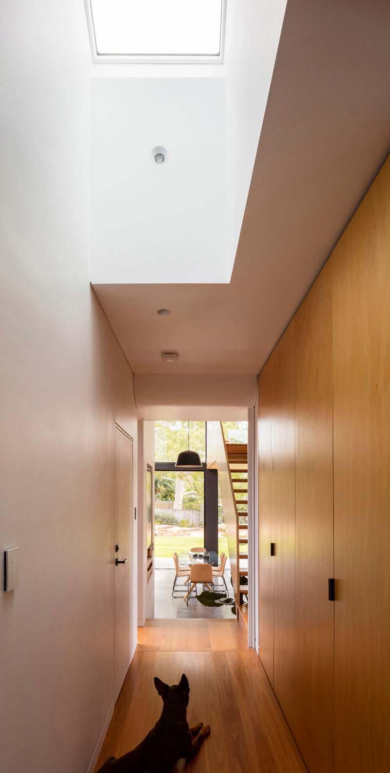 This house features a hallway lined with wood closets that leads to the new extension, and a skylight adds natural light to the interior. #Hallway #InteriorDesign #Skylight 