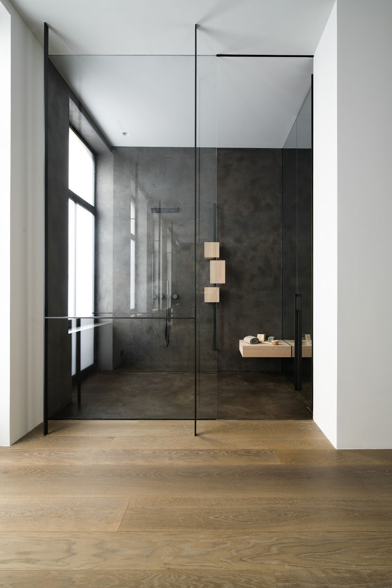 This modern bathroom has wood floors and a walk-in shower that's enclosed behind a glass shower screen. #BathroomDesign #ModernBathroom #ModernShower