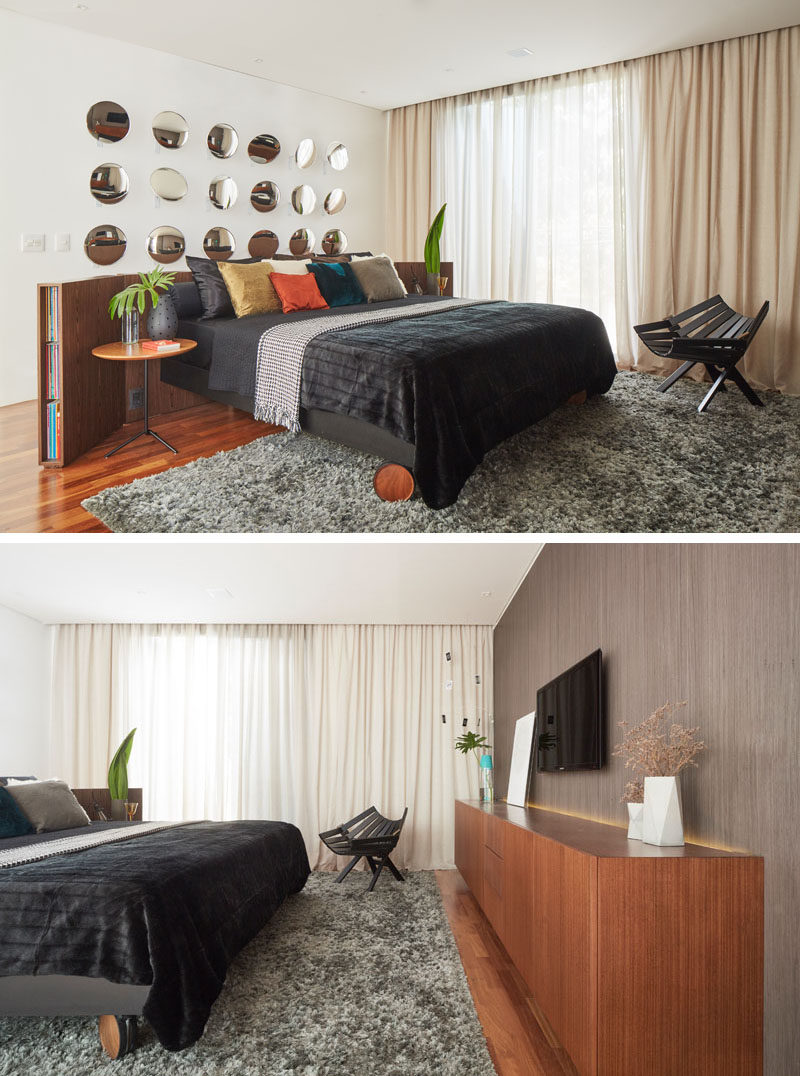 In this modern bedroom, the bed has been placed in the center of the room, with a curved wood headboard. Round mirrors on the wall reflect the sunlight and the cabinetry on the opposite wall. #ModernBedroom