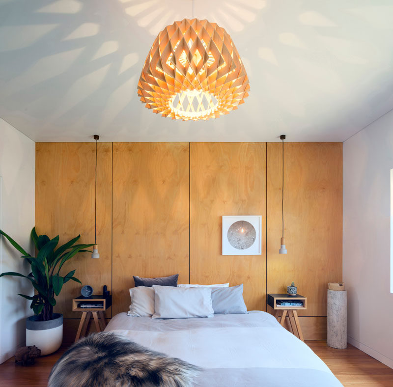 In this contemporary master bedroom, wood covers an entire wall and acts as a headboard for the bed. #BedroomDesign #WoodAccentWall