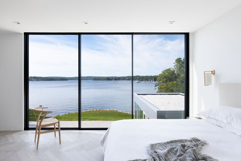 In this modern bedroom, black framed floor-to-ceiling windows perfectly highlight the water view. #Windows #Bedroom