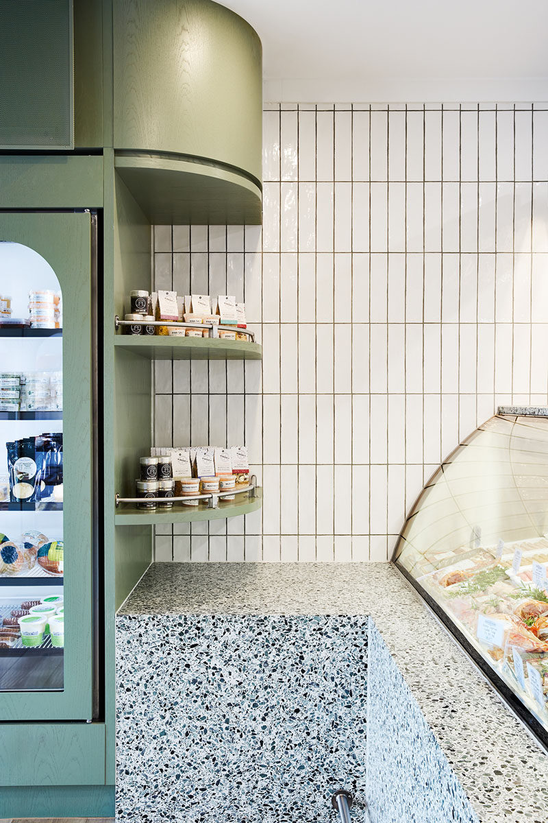 A calming soft green and white color palette has been used throughout the interior, while wood floors define the retail area of this modern butcher and add a natural element. #ModernButcher #ModernRetail #Shelving #RetailDesign #InteriorDesign