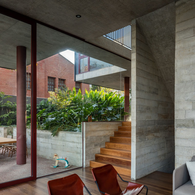 Exposed board formed concrete walls line the stairs that connect the various floors of this modern house. #ConcreteWalls #GlassWalls #Architecture