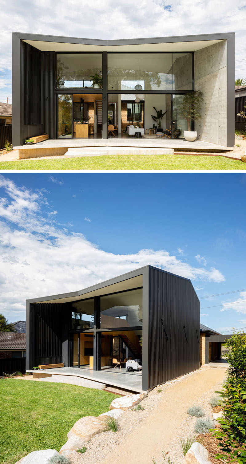 The living area of this modern house opens up to a covered outdoor patio, and at the side of the house, there's a path that leads from the garage to the backyard. #ModernHouseExtension #ModernArchitecture