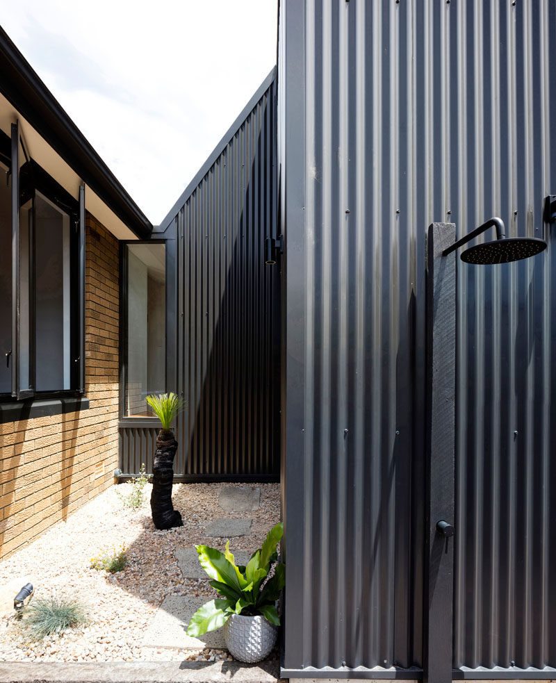 A modern black house extension was added to a brick house in Australia. #ModernArchitecture #OutdoorShower