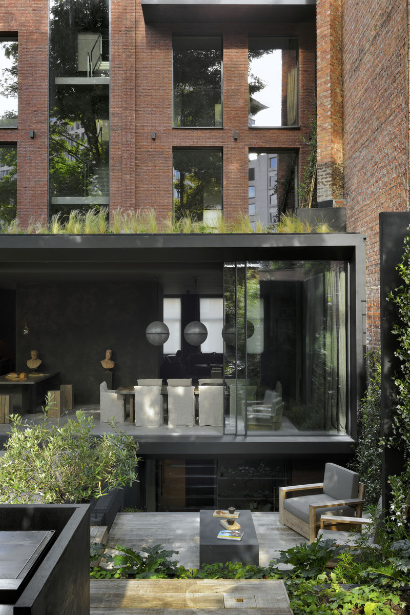 The renovation of this brick home allowed for a new extension to the back of the house, which has large sliding glass doors that open to the updated rear garden. #ModernArchitecture #Landscaping