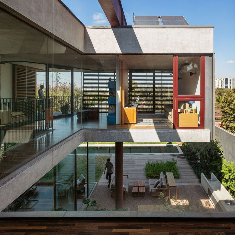 The top floor of this modern house has glass walls and a balcony that side garden, backyard, and swimming pool. #GlassWalls #ModernHouse