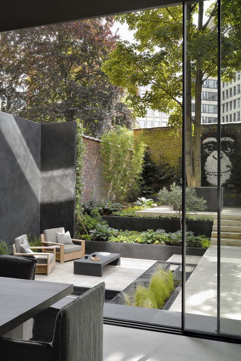 This modern garden has been landscaped with various levels, creating places for the home owners to relax in the lounge, or take in the mural on the back brick wall. #Landscaping #GardenDesign