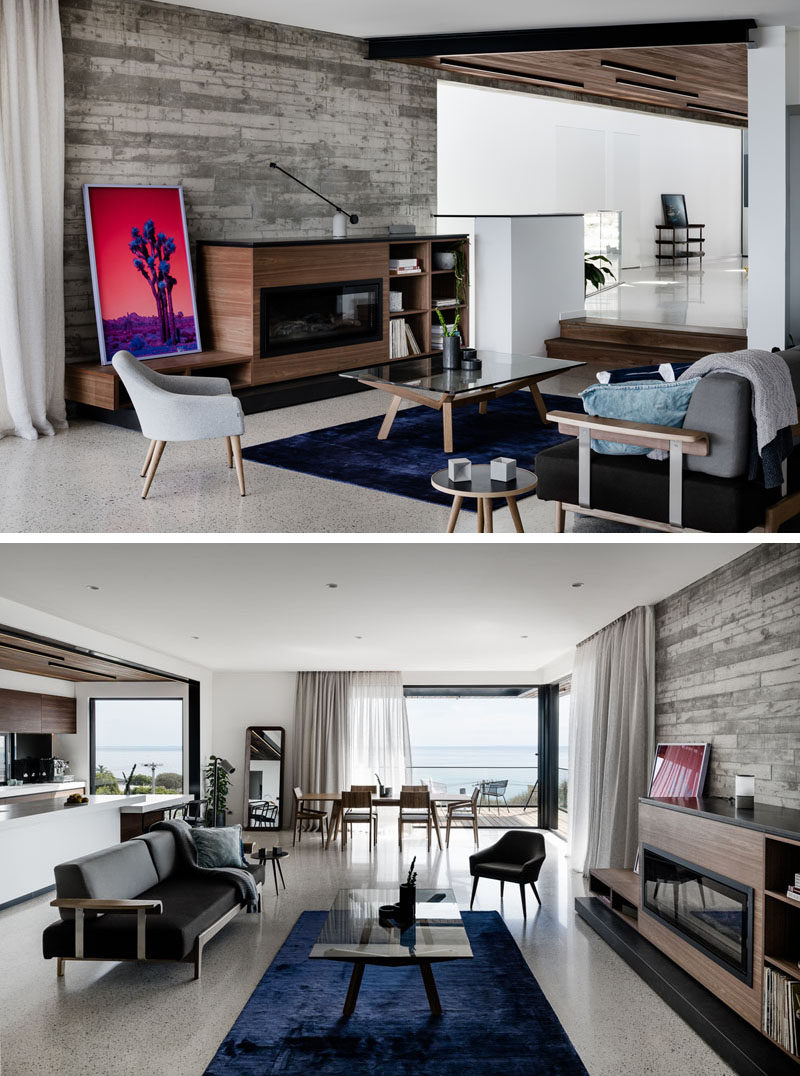 The entryway of this modern house steps down to the living room, where there's exposed concrete walls that contrast the wood elements of the interior, like the spotted gum timber lined ceiling. #LivingRoom #OpenPlanInterior #WoodCeiling #ConcreteWall