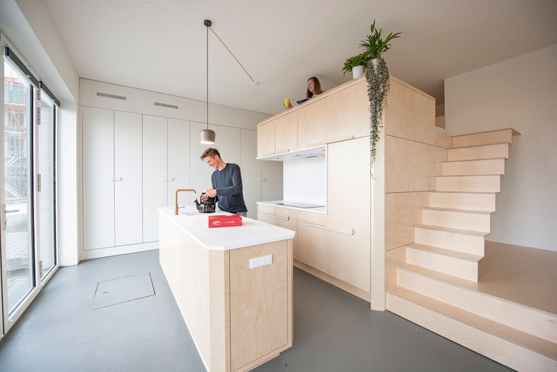 This modern loft apartment has a subtle palette of birch wood and white Corian. There's a bathroom, storage room, kitchen, raised living room, and a lofted bedroom. #InteriorDesign #ApartmentDesign #Loft