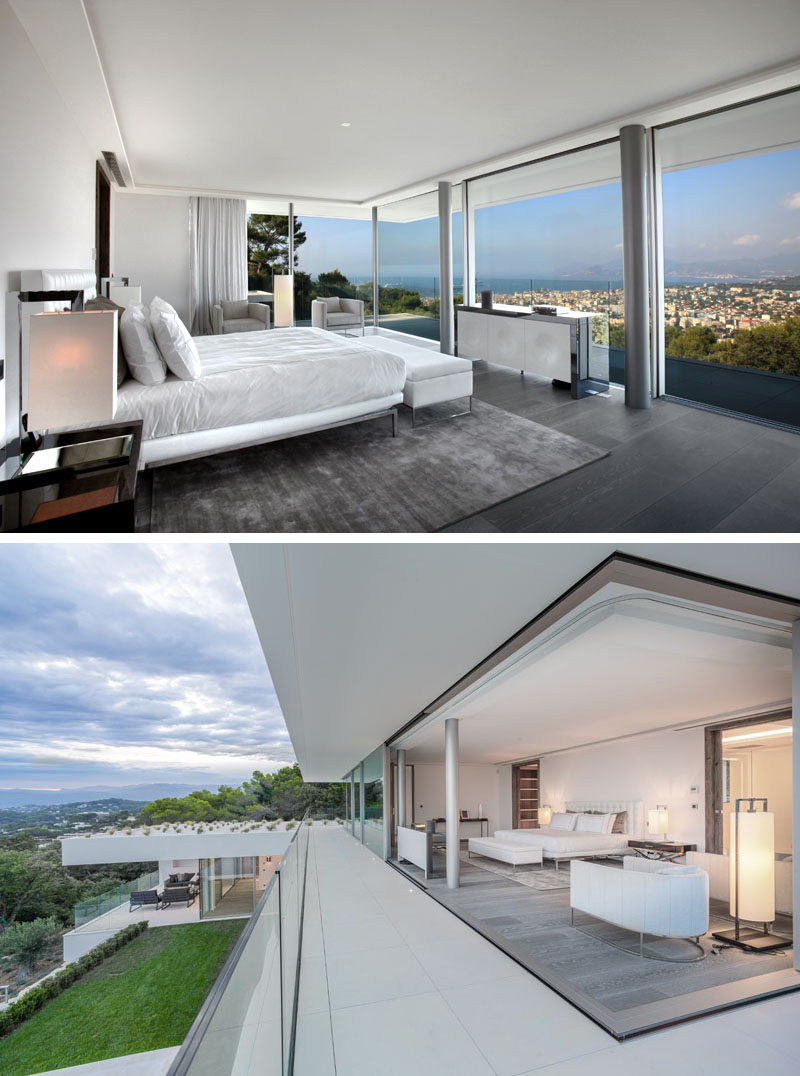 This modern master bedroom suite has minimalist window panels that slide entirely into the walls to transform the rooms into open terraces. Glass balcony railings help to create a seamless view of the surrounding area. #MasterBedroom #GlassWalls