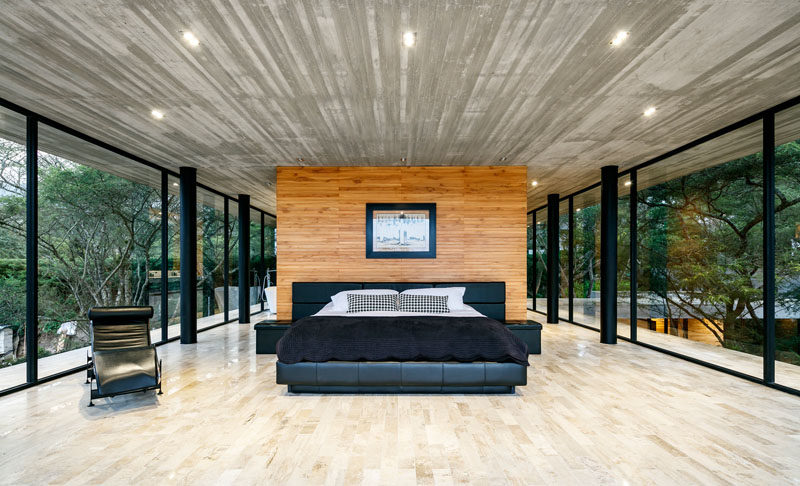 This modern master bedroom is spacious and open, and has the feeling of being in the trees due to the glass walls that surround it. #MasterBedroom #BedroomDesign #Windows