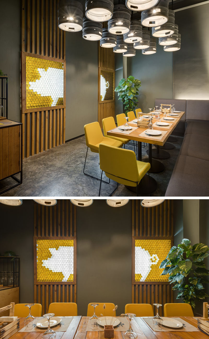 This modern brew pub and restaurant has a small private dining area with beer kegs that have been repurposed as lighting, while on the wall, decorative pig artwork is highlighted. #RestaurantDesign #Lighting #InteriorDesign