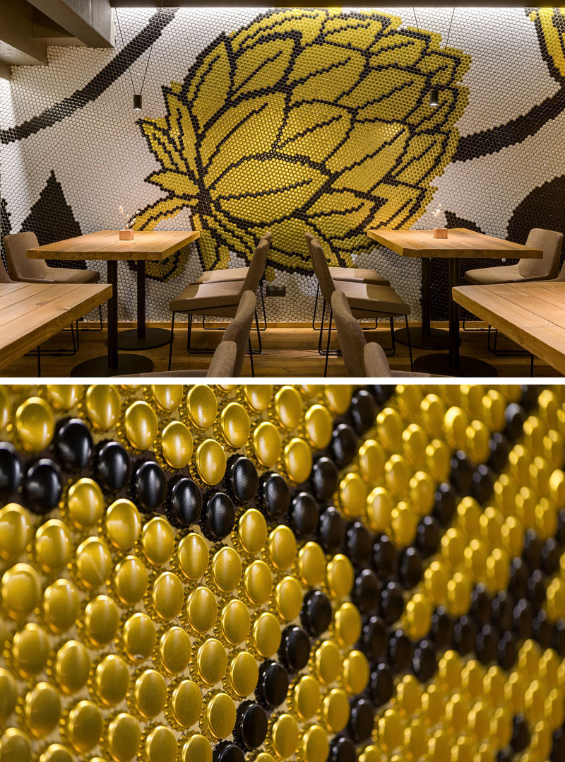 Drawing inspiration from the beer making process, a large wall mural in the form of a hop flower decorates the wall of this brew pub and restauant in silver, gold, and black. #Mural #RestaurantDesign #BarDesign