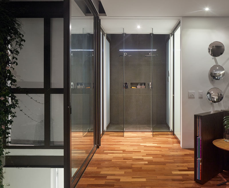 This master bedroom features an exposed glass enclosed shower. While, white doors on either side of the shower lead to the washroom and a walk-in closet. #Bathroom #GlassEnclosedShower