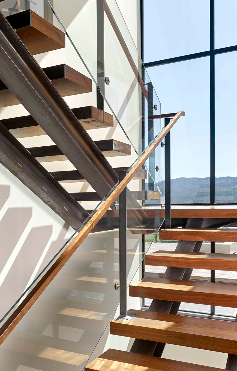 Steel and wood stairs with a glass handrail lead up to the second floor of this modern house. #Stairs #StairDesign #ModernStairs