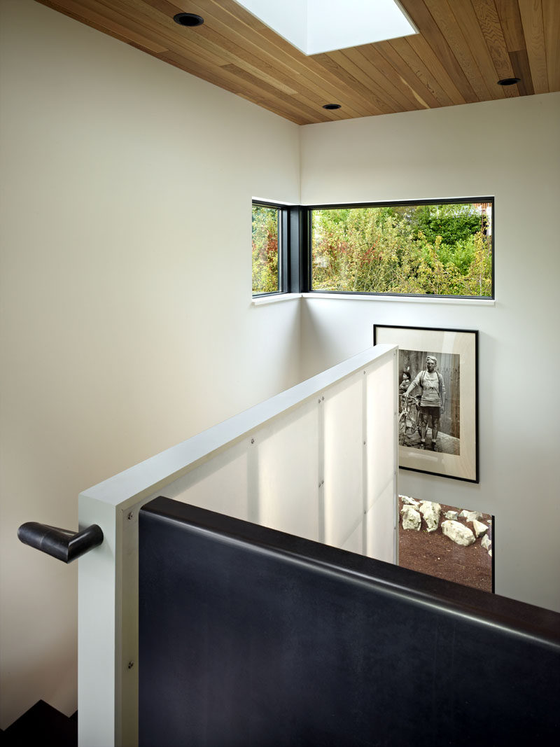 At the top of these modern stairs are a couple of black framed windows that provide a view of the trees, while above, a skylight adds natural light to the stair well. #Windows #Skylight