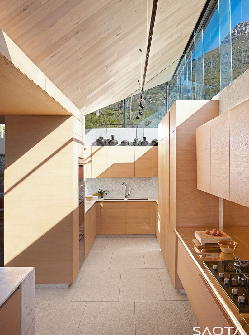 This modern kitchen features light colored wood cabinetry, while the windows provide natural light and views of the mountains. #ModernWoodKitchen #KitchenDesign #Windows