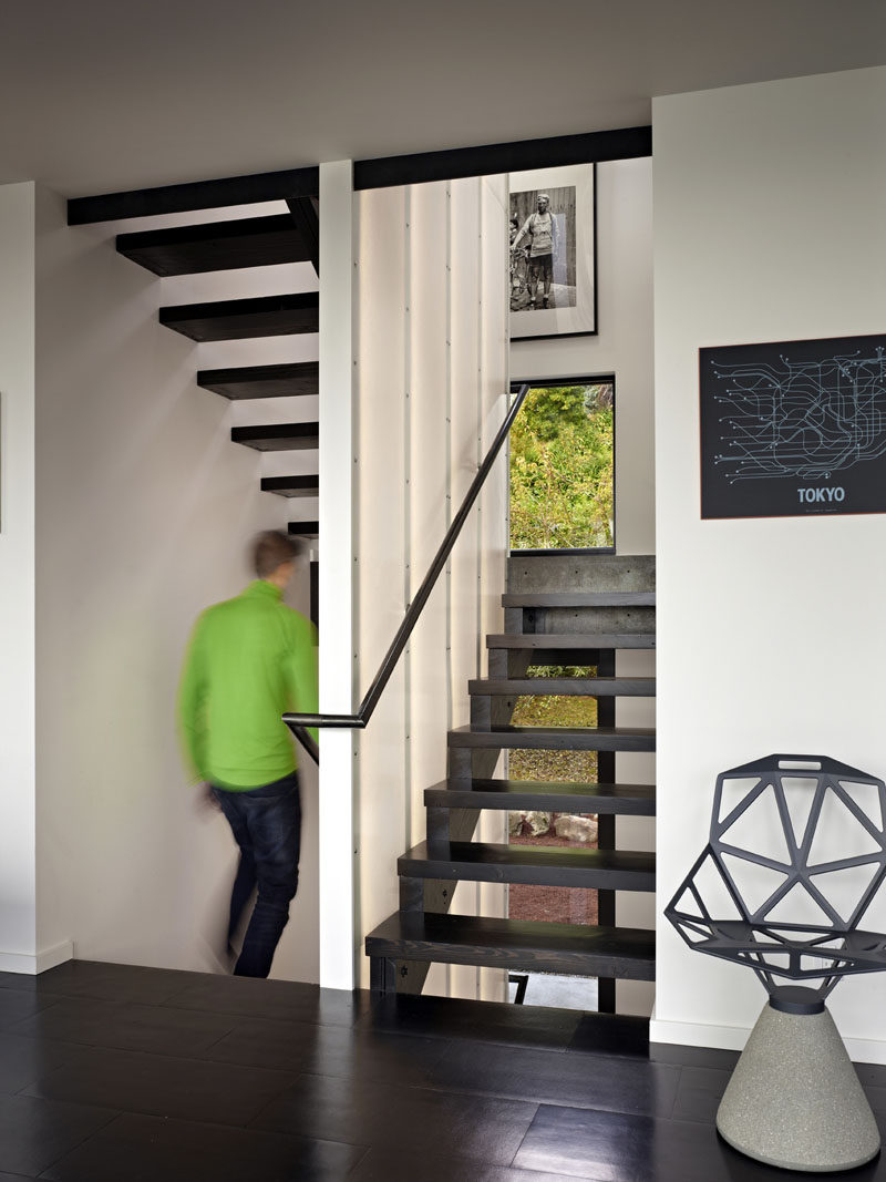 Stairs connecting the various levels of this modern house, and have been created using reclaimed wood and steel. The stair winds around an interior wall of backlit translucent fiberglass. #ModernStairs #StairDesign