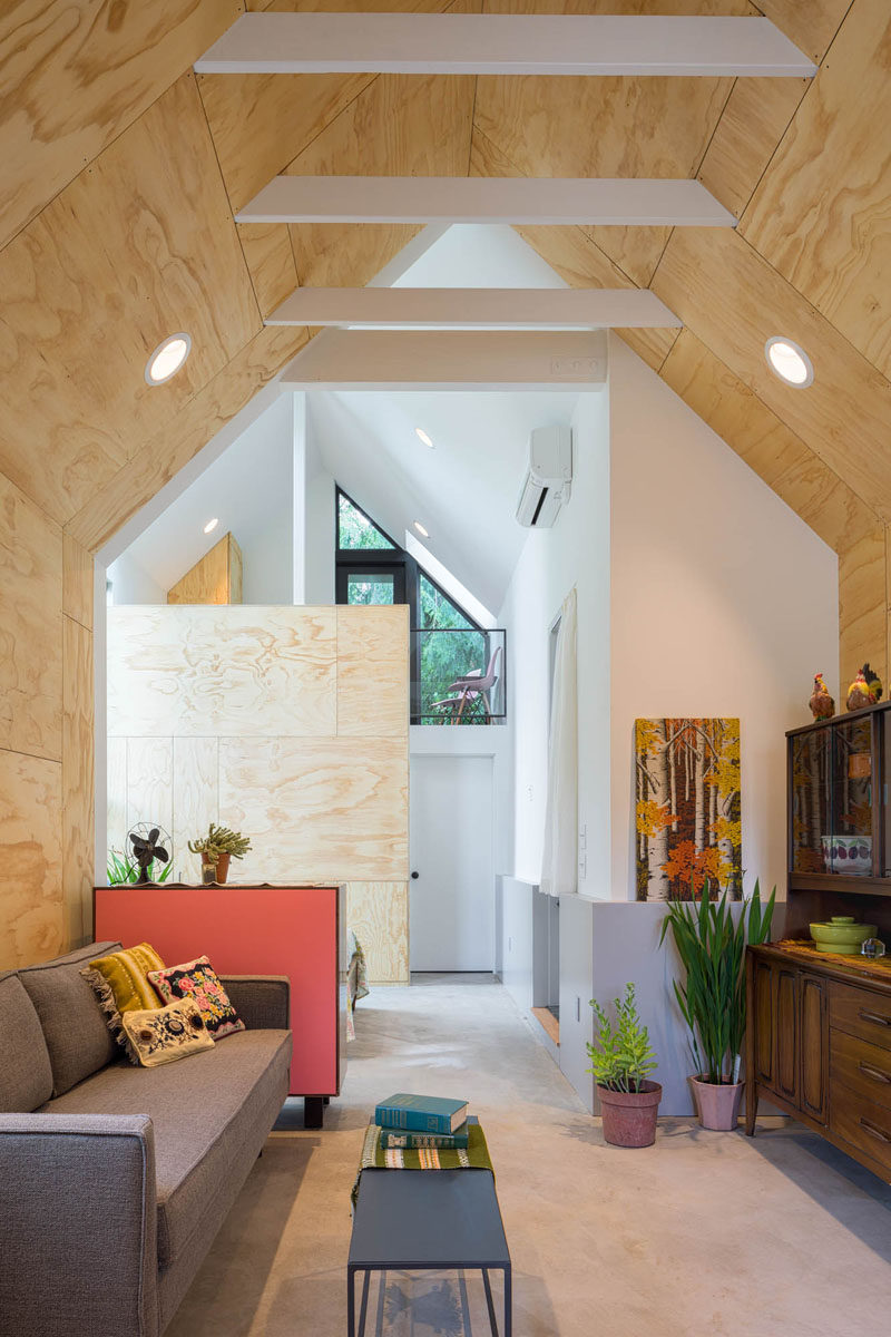 This tiny house features an open floor plan, a high pitched ceiling with exposed white rafters, and a loft area. #TinyHouse #InteriorDesign #Architecture