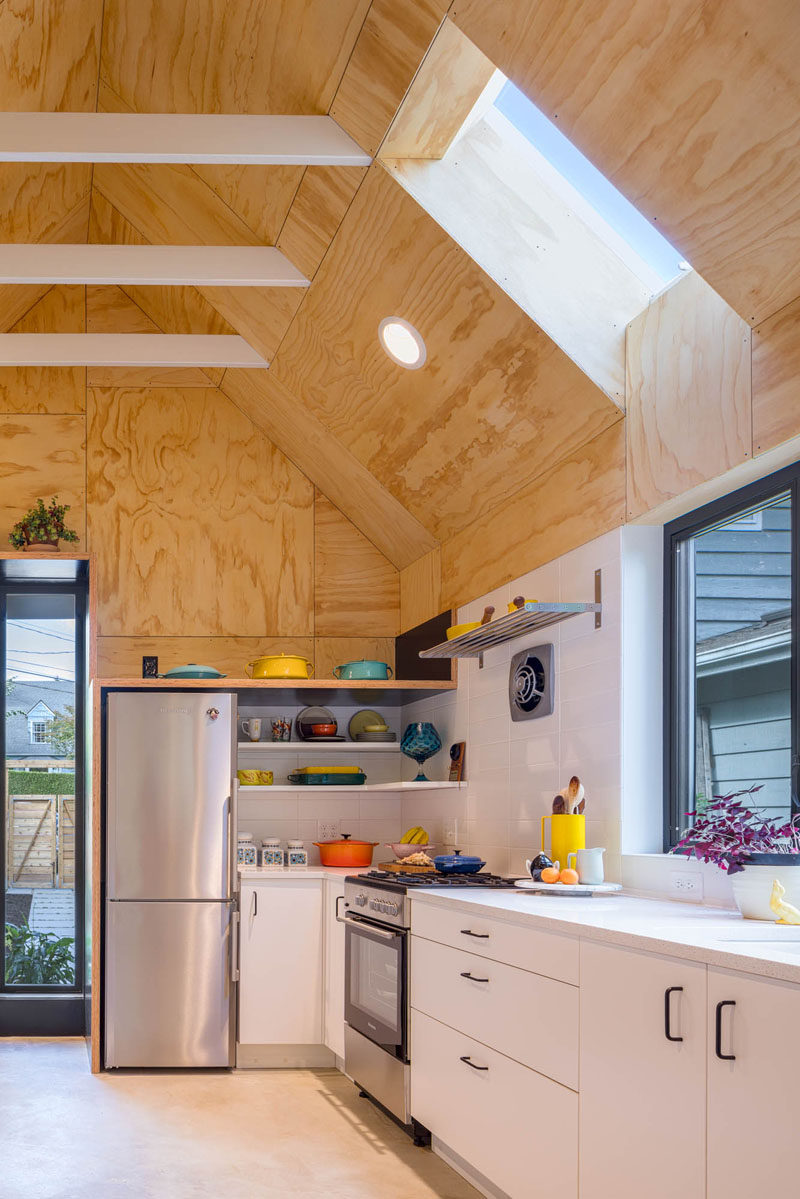 The interior of this tiny house features custom plywood panel walls, polished concrete flooring, and a full-size kitchen. #TinyHouse #SmallLiving #KitchenDesign