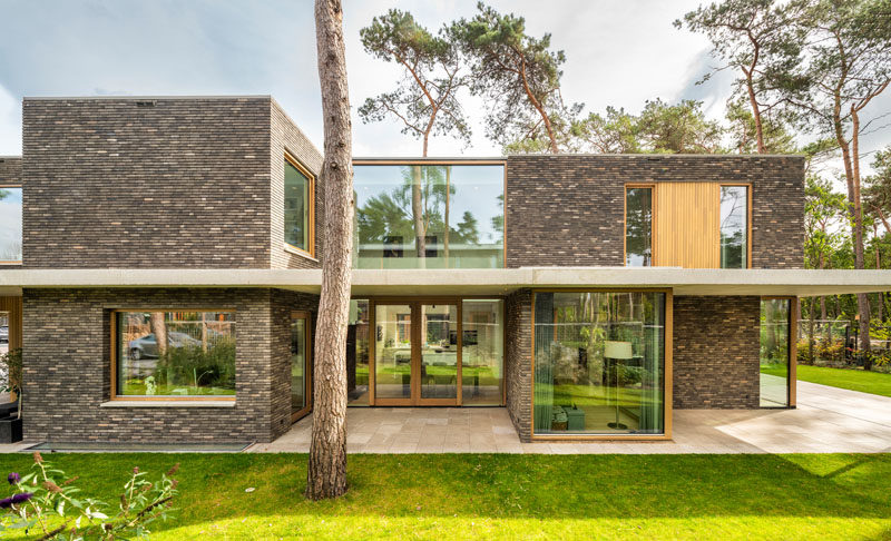 The exterior of this modern house features brick volumes that are separated by a concrete canopy, providing a strong horizontal line to the vertical nature of its surroundings. #ModernHouse #Brick #Concrete #Architecture