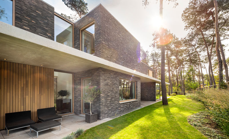 The exterior of this modern house features brick volumes that are separated by a concrete canopy, providing a strong horizontal line to the vertical nature of its surroundings. #ModernHouse #Brick #Concrete #Architecture