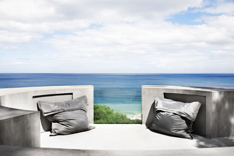 This modern house has a curved concrete rooftop seating area that allows for views of the ocean. #OutdoorSeating #Rooftop