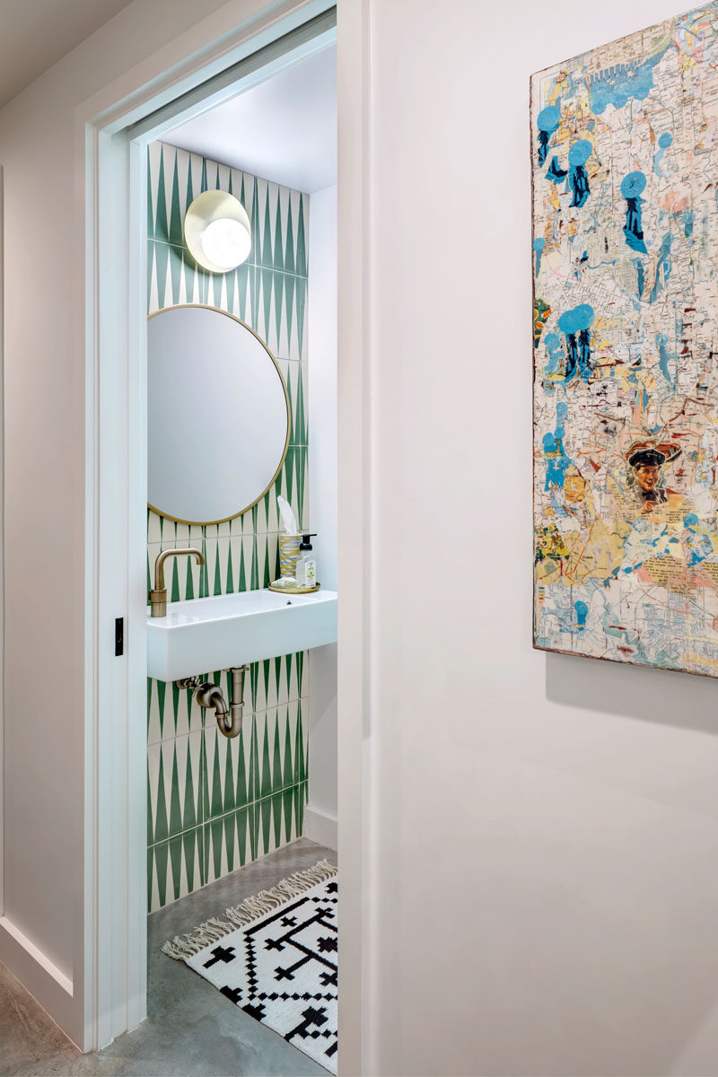 In this simple bathroom, decorative tile is combined with a round mirror and a simple white vanity for a contemporary appearance. #BathroomDesign #Bathroom