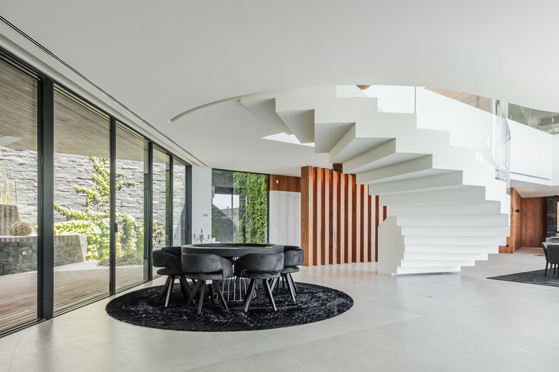 This modern house has a round table that's anchored in the open interior by a dark area rug that reflects the shape and color of the table. #DiningTable #RoundTable #InteriorDesign