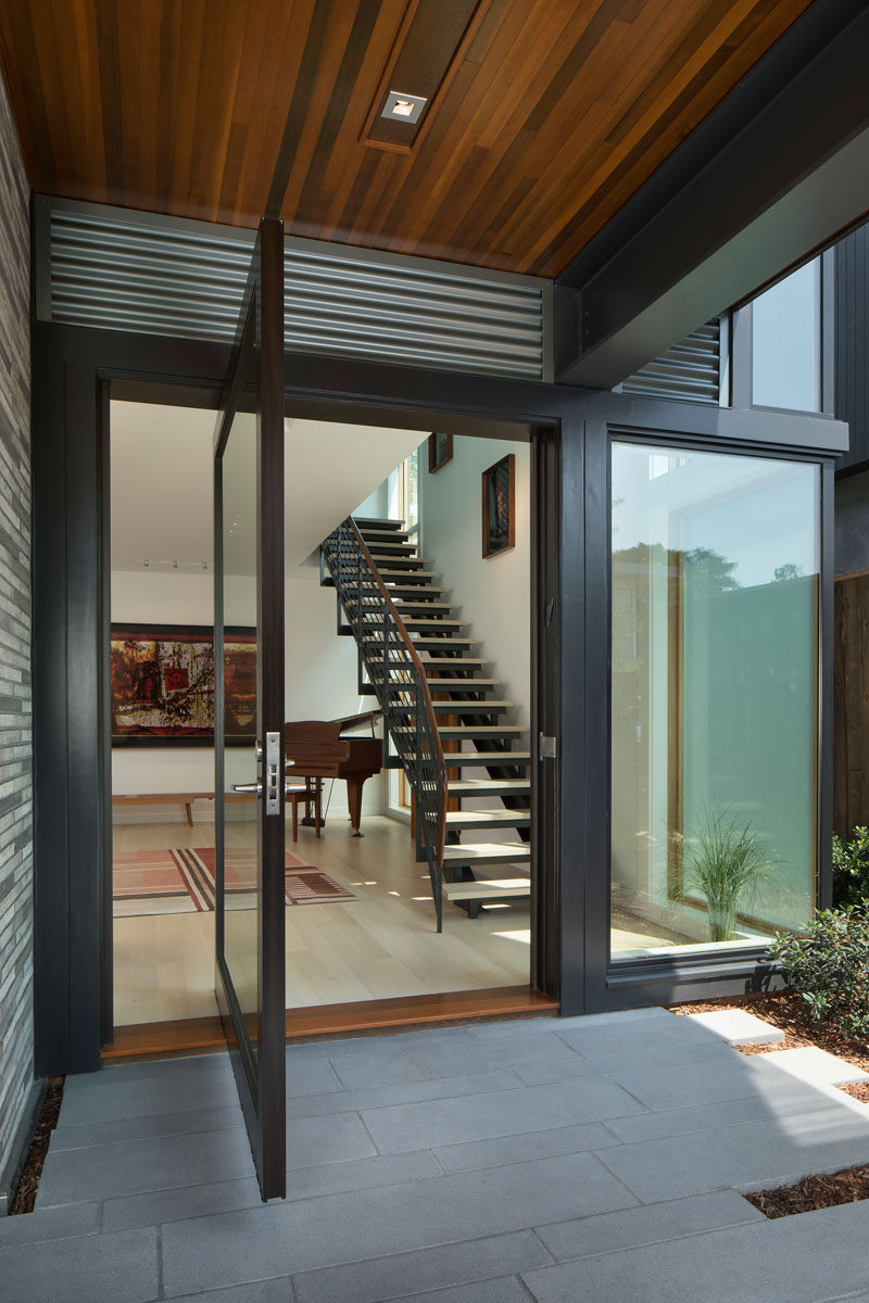 A large glass pivoting front door welcomes visitors to this modern house. #PivotingFrontDoor #FrontDoor