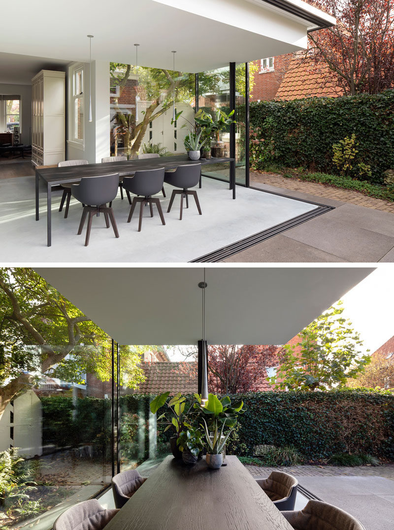 When the glass walls of this modern house extension are open, the home owners now have a semi-enclosed outdoor space that allows them to enjoy the back garden. #DiningRoom #ModernHouseExtension #GlassWalls