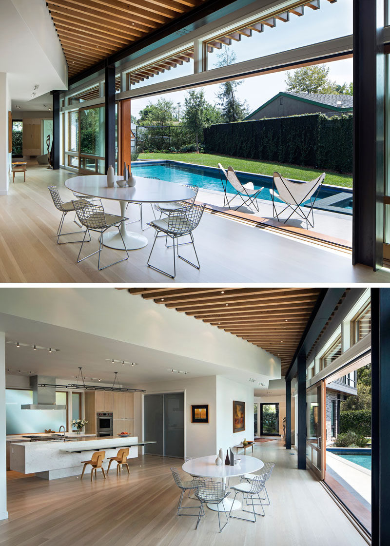 The entryway of this modern house leads to a dining area with oversized 8-ft by 10-ft sliding glass panel doors that open directly to the pool, creating a seamless indoor-outdoor environment. #ModernHouse #GlassDoors #SwimmingPool