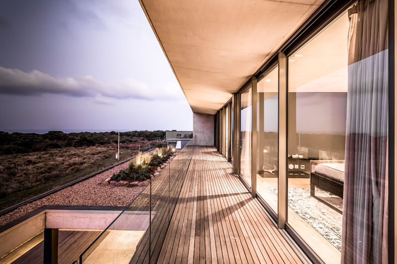 A long balcony runs the length of this modern home's upper floor, and provides views of the surrounding area and the small garden on the roof of the lower level. #Balcony #Architecture