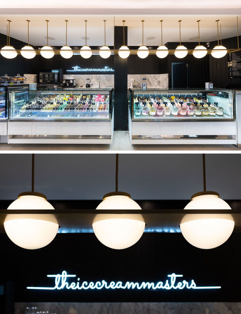 Lighting above the ice cream display draws the customers eye in this cafe, while a neon light sign brightens up the black wall. #Lighting #RetailDesign