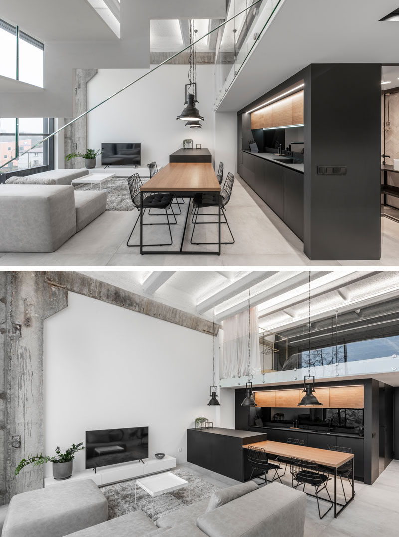 Separating the living room and kitchen in this modern loft apartment, is an island that drops down to become a wood dining table for four. #DiningTable #BlackKitchen #InteriorDesign